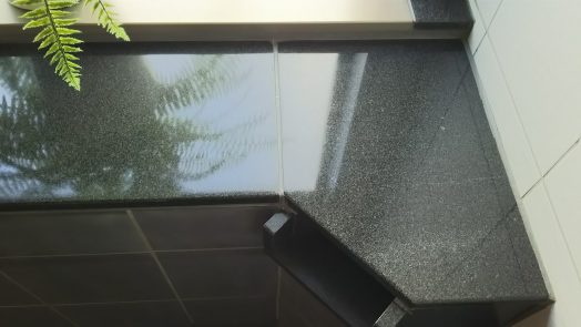 ホテル旅館大浴場の黒御影石浴槽笠石についた頑固な水垢を除去した後、鏡面研磨する